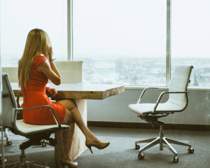 A woman looks out a large office window