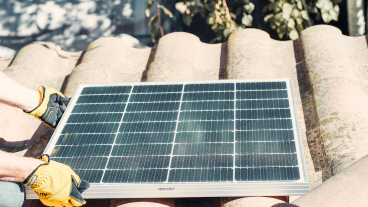 A clean solar panel is being placed on a roof